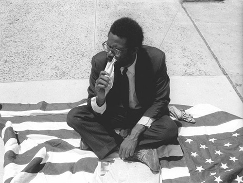 Pope.L, Eating the Wall Street Journal, 1991. Crédit photo : James Pruznick. Courtesy The Estate of Pope.L et Mitchell-Innes & Nash, New York. © The Estate of Pope.L.